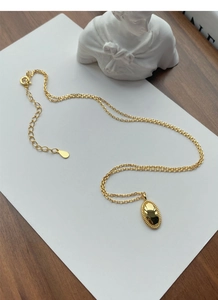 Makroaufnahme von goldenem Oval-Anhänger mit Perlenrand und verstellbarer Kette