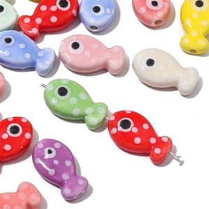 Dettaglio di perline colorate in ceramica a forma di pesce con pois bianchi per gioielli