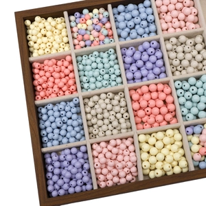 Macro detail of macaron acrylic beads organized in a wooden storage box for DIY jewelry