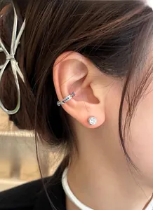 Close-up of colorful zircon cartilage cuff and round stud earring on model's ear