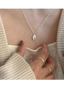 Nahaufnahme der minimalistischen S925 Silber Halskette mit ovalem Anhänger und Ringen