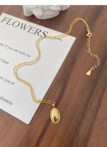 Detailaufnahme der goldenen Halskette mit ovalem Anhänger und verstellbarem Verschluss