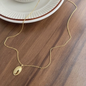 Elegante S925 Silberhalskette in Gold mit ovalem Perlenanhänger auf Keramikteller
