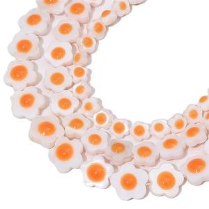 Macro detail of floral shell beads for jewelry making with pearlescent white and orange finish