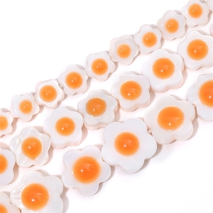 Macro shot of white shell flower beads with orange centers for DIY jewelry making