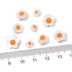 Macro shot of egg-shaped shell flower beads with ruler for size measurement reference