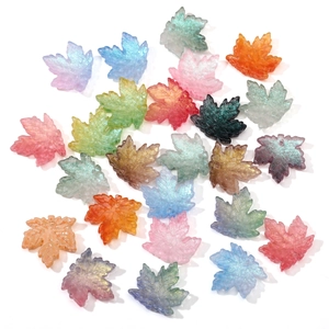 Close-up of colorful maple leaf glass beads with glitter texture for DIY jewelry making