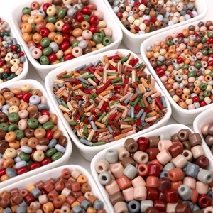 Assorted colorful glass craft beads in square ceramic bowls for DIY jewelry making