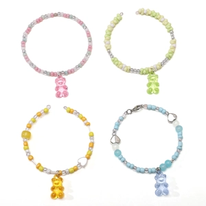 Close-up of four colorful DIY beaded bracelets with transparent resin gummy bear charms