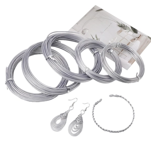 Silver jewelry craft wires with handmade earrings and bracelet on white background