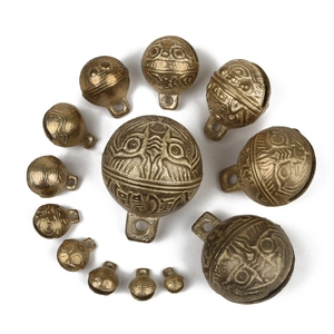 Set of 13 vintage brass tiger head bells in spiral layout on white background