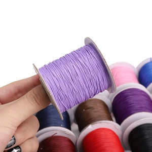 Handgehaltene lila gewachste Kordelspule für DIY-Schmuck mit buntem Hintergrund-Set