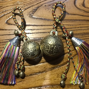 Detailed macro of vintage brass tiger bells with colorful woven tassels and silk threads