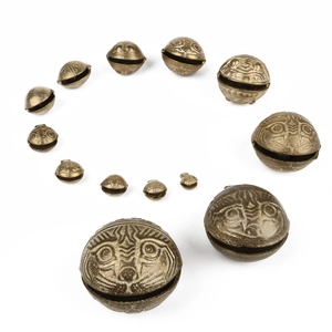 Set of vintage brass tiger head bell pendants in various sizes on white background