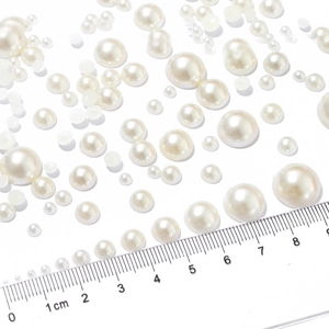 Flat lay of mixed size creamy white ABS flatback faux pearls with iridescent luster