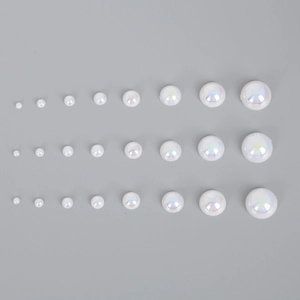Flat lay of iridescent aurora half round ABS pearl beads in eight sizes for DIY crafts