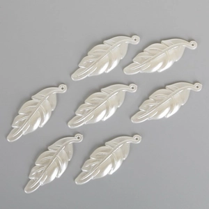Detalle macro de colgantes de hoja nacarada blanca con agujeros para joyería artesanal