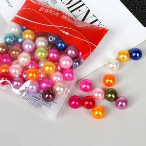 Mix of colorful ABS pearl beads spilling from a transparent pouch for DIY jewelry making