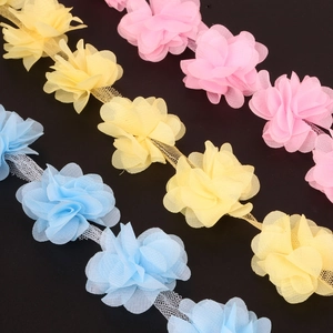 Macro shot of 3D chiffon flower lace trim in pastel blue, yellow and pink on black