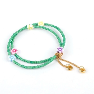 Handmade beaded bracelet with green seed beads, colorful clay flowers and gold extension chain