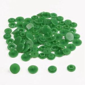 Detail of green resin snap fastener set showing cap, socket, stud, and post components