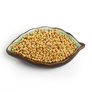Close-up of golden metal spacer beads in a leaf-shaped ceramic dish for DIY jewelry