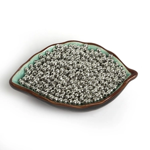 Close-up of small silver iron spacer beads for jewelry making in a leaf-shaped ceramic dish