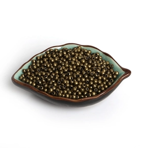 Macro view of vintage bronze metal spacer beads for DIY jewelry making in a ceramic bowl