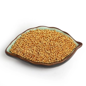 Golden iron round spacer beads with large holes in a leaf-shaped ceramic tray for DIY jewelry
