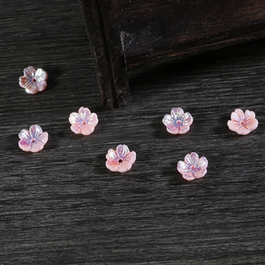Vista macro detallada de siete cuentas de flores de resina rosa nacarada sobre madera