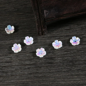 Detalle macro de cuentas de resina de flor de cerezo irisadas sobre fondo de madera DIY