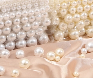 Detailed view of various sizes of cream round imitation pearls on champagne satin fabric