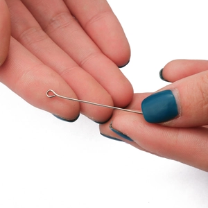 Silver eye pins for DIY jewelry making held by hand showing bright metal finish