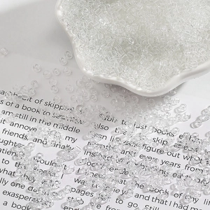 Macro shot of 2-4mm clear glass seed beads for DIY jewelry making in a white ceramic dish