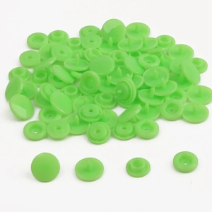 Macro detail of bright green resin snap fasteners kit showing components for DIY clothing