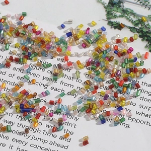 Assorted colorful glass tube beads for DIY jewelry making scattered on vintage paper