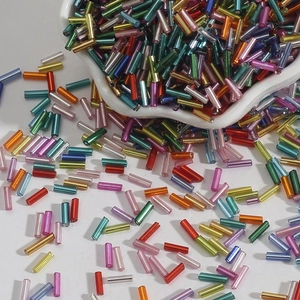 Close-up of colorful cylindrical glass bugle beads for DIY embroidery in a white bowl