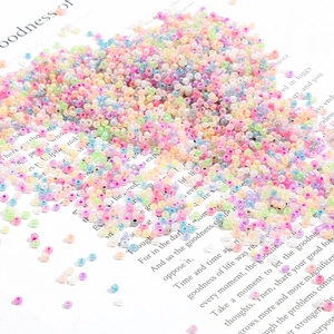 Macro shot of 2mm macaron colored seed beads scattered on decorative paper for DIY craft