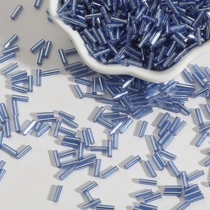 Macro shot of light blue glass bugle beads in a ceramic bowl for DIY jewelry making