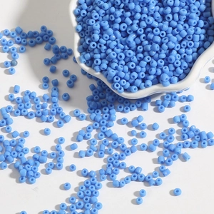 Close-up of light blue glass seed beads for DIY jewelry making in a white ceramic bowl