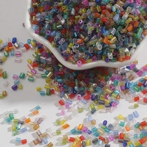 Macro shot of 2mm colorful glass tube beads spilling from a white bowl for DIY jewelry