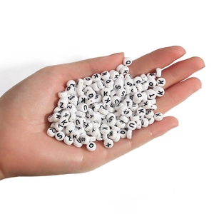 White round acrylic alphabet beads for DIY jewelry making held in hand over white background
