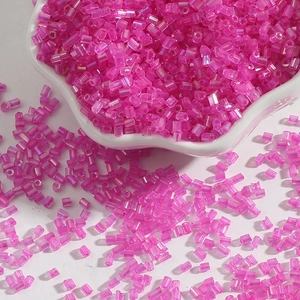 Close-up of rose pink bugle beads in a ceramic bowl for DIY jewelry and embroidery