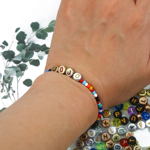 DIY colorful acrylic bead bracelet with golden JOJO alphabet letters worn on a wrist