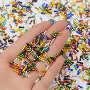 Macro shot of colorful metallic bugle beads held in hand for handmade DIY jewelry crafts