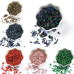 Colorful glass bugle beads in porcelain bowls for DIY jewelry and embroidery crafts