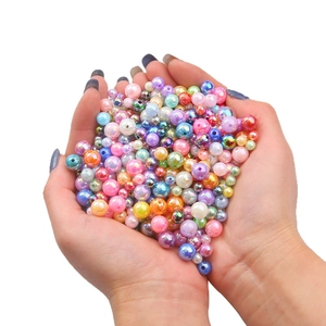 Handheld assortment of iridescent acrylic pearl beads in pastel colors for DIY jewelry making