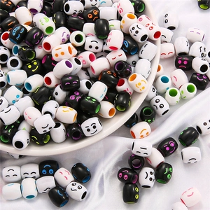 Cylindrical acrylic emoji beads for DIY crafts on a white ceramic tray and satin