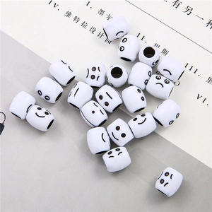Macro shot of white acrylic cylinder beads with various emoji smiley faces for DIY jewelry