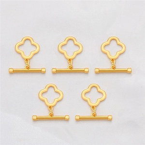 Detailed macro view of five 18K gold-plated clover-shaped OT toggle clasps on white silk